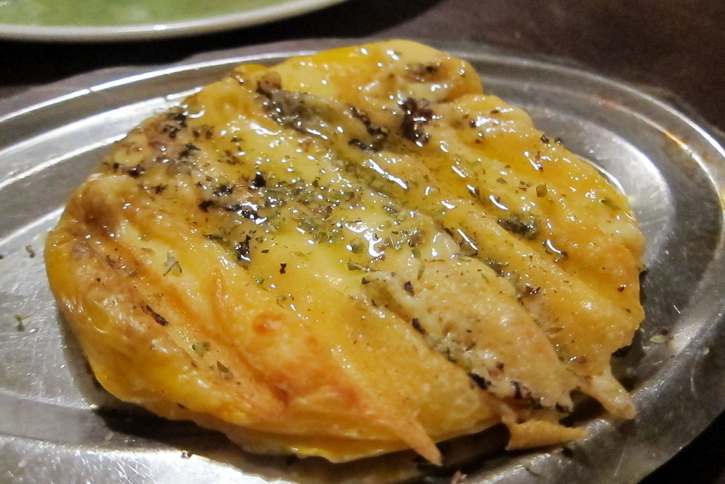 Bubbling Argentine provoleta in a cast-iron skillet with herbs