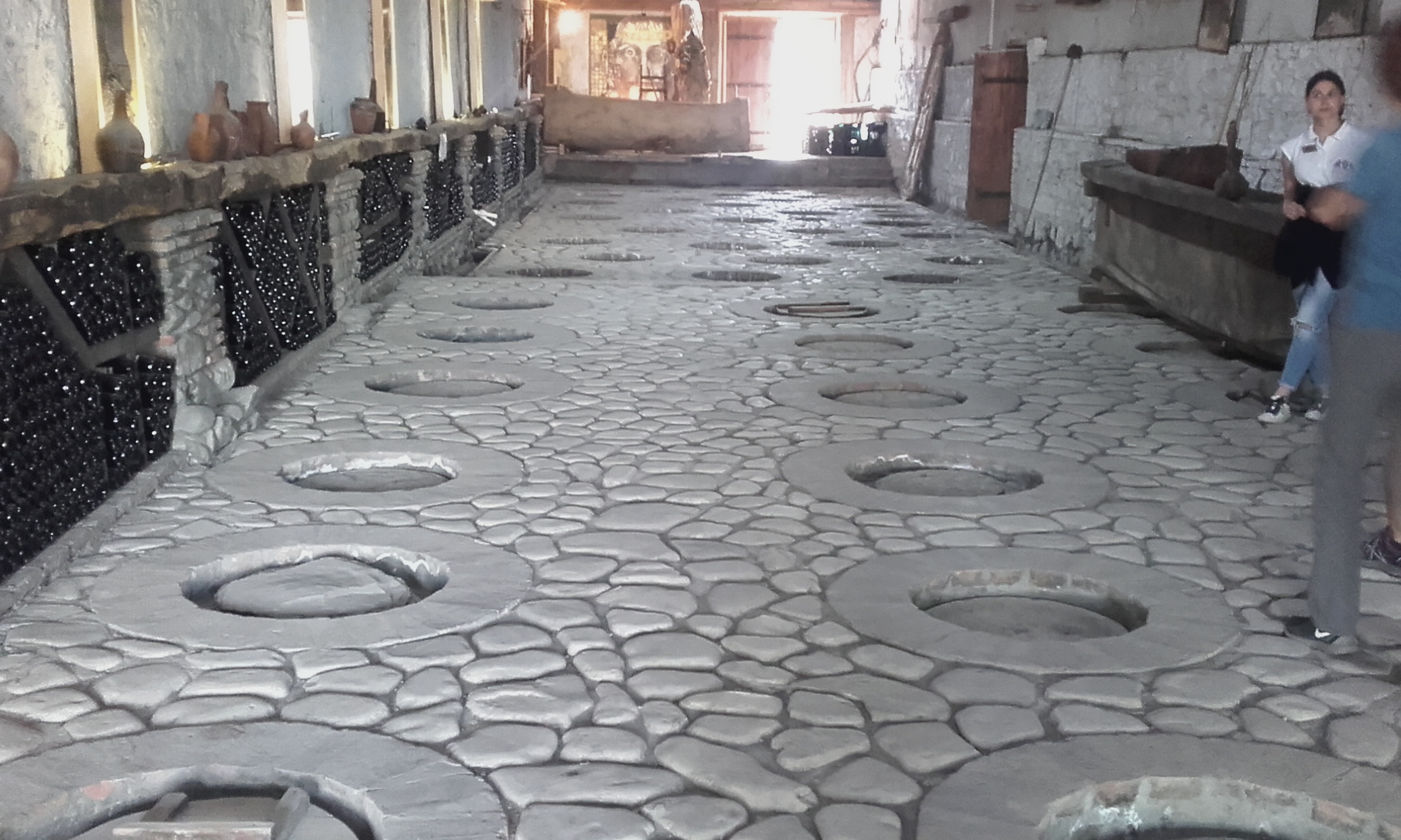 Traditional qvevri openings set into the stone floor of a Georgian wine cellar.