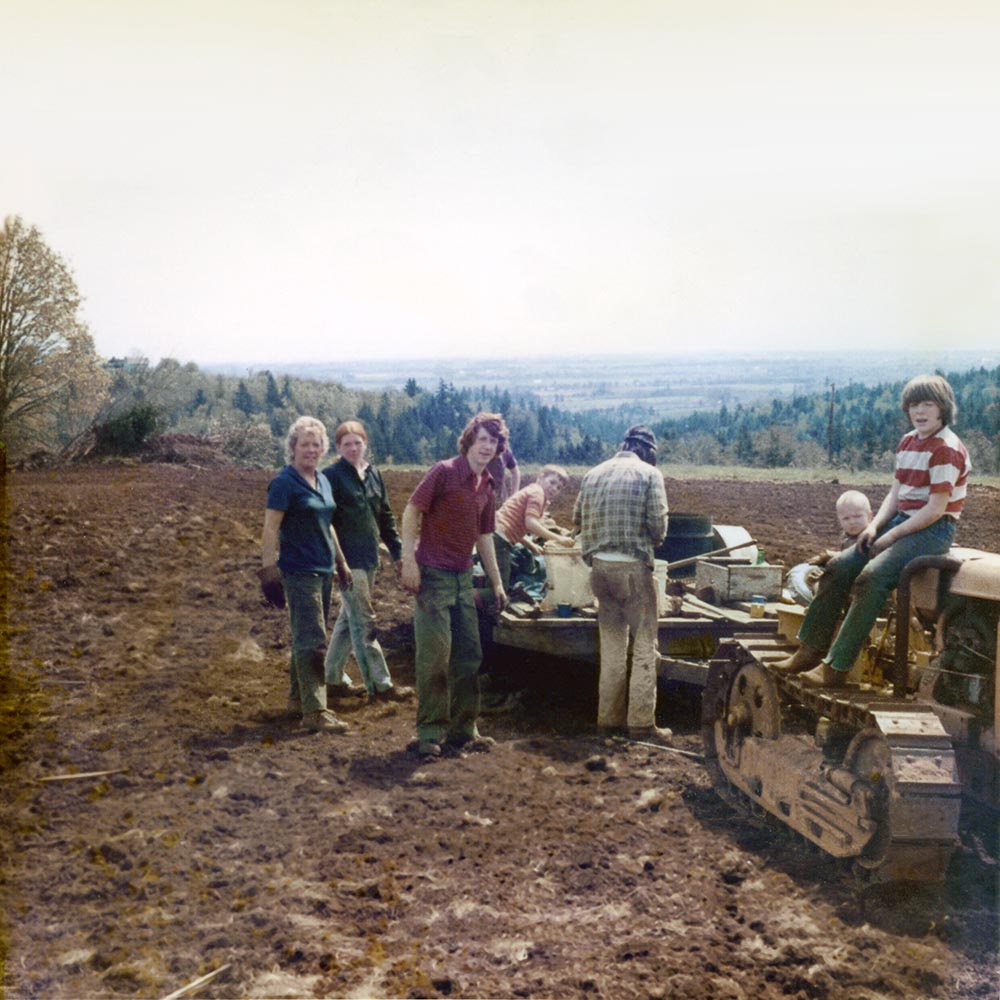 People and children beside a tractor while planting a hillside vineyard in 1972.